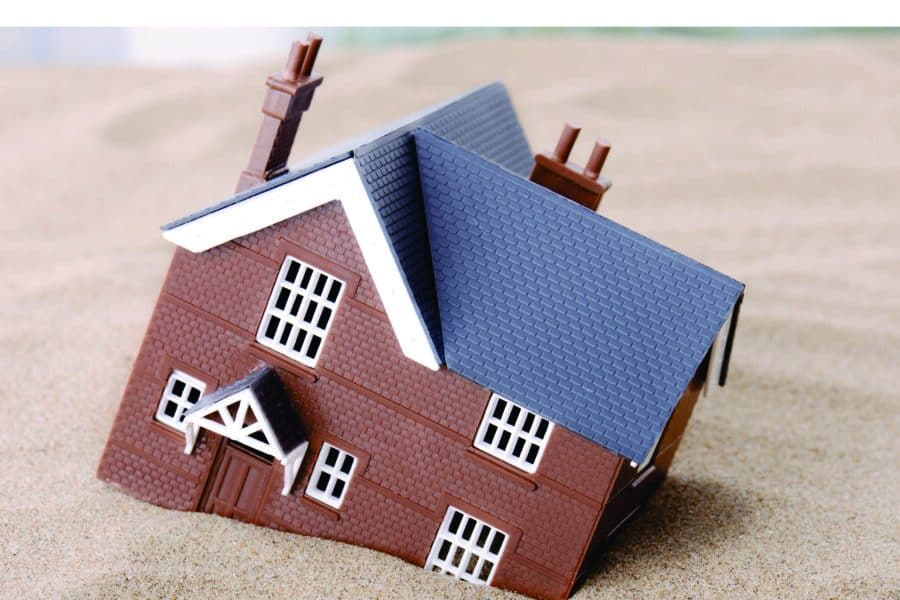 A small model house with a blue roof and brown walls.