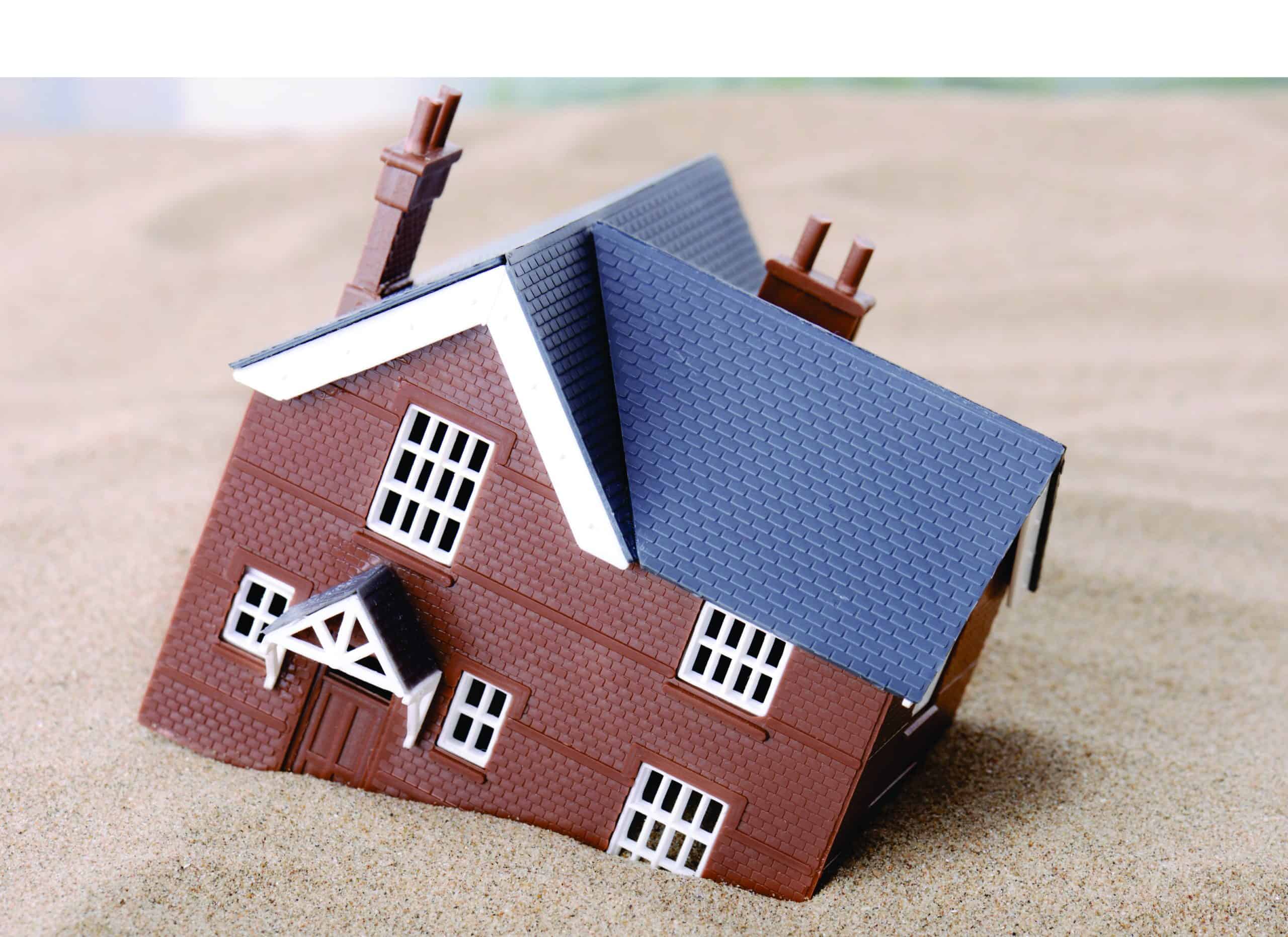 A small model house with a blue roof and brown walls.