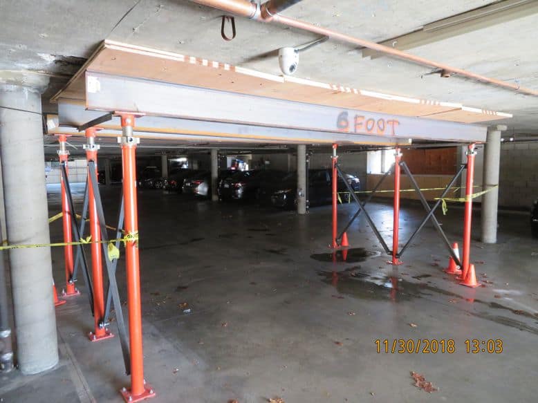 Temporary shoring installed under actively spalling concrete in a parking structure — Stage 3 deterioration.