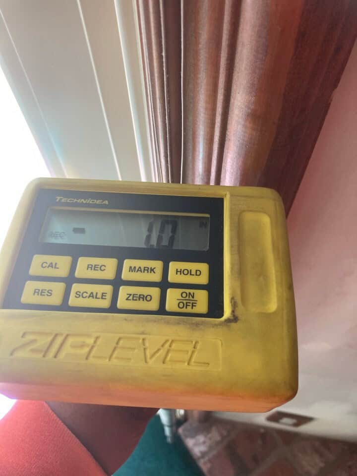 Ziplevel precision instrument verifying foundation settlement levels at a residential property inspection