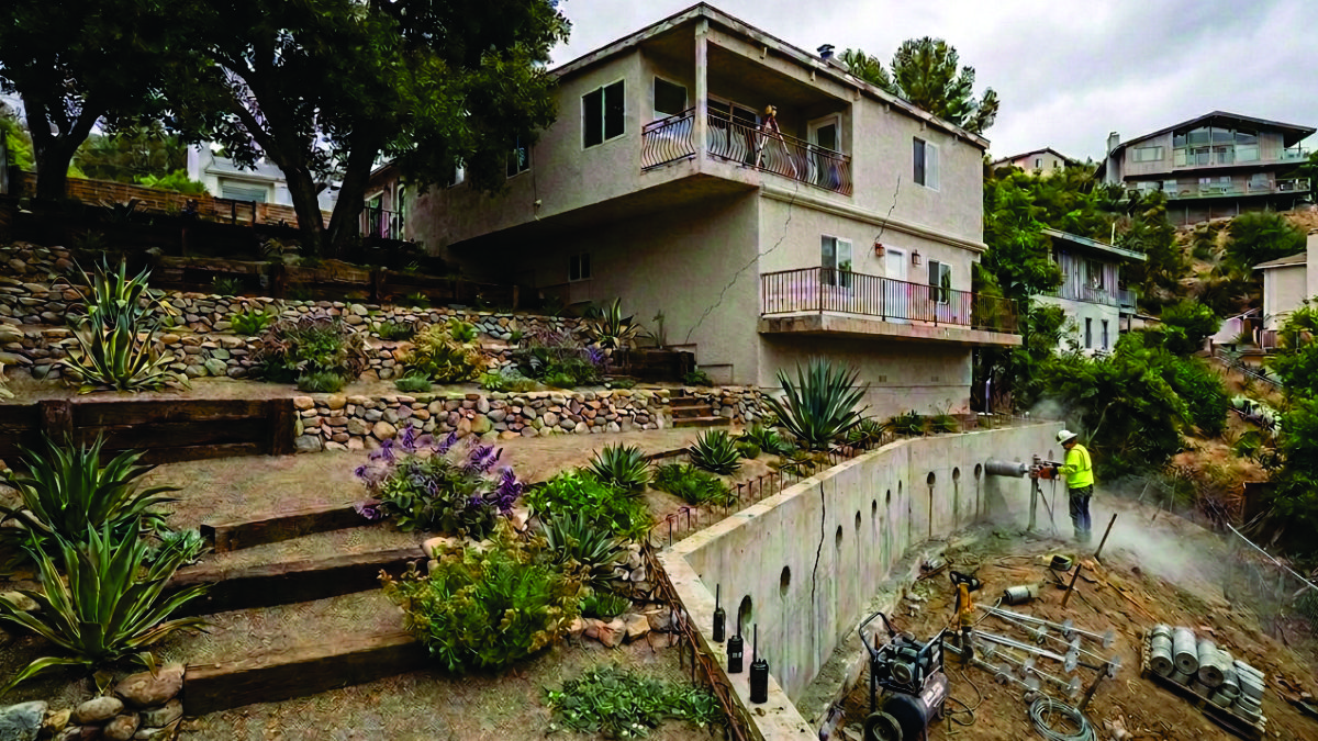Helical tie-backs being installed to stabilize a failing retaining wall at a Woodland Hills property